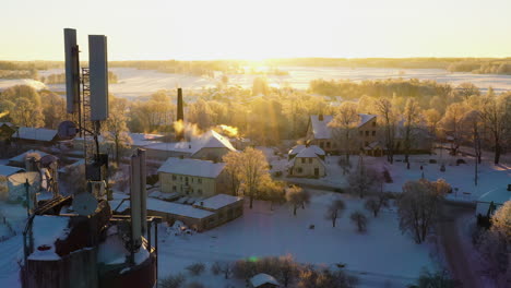 Cold-snow-covered-winter-morning-in-rural-village-on-golden-hour,-aerial-view