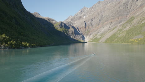 Barco-Navegando-En-El-Fiordo-De-Lyngen-Con-Montañas-Rocosas-De-Los-Alpes-Escandinavos-En-Segundo-Plano-En-Un-Día-Soleado,-Noruega