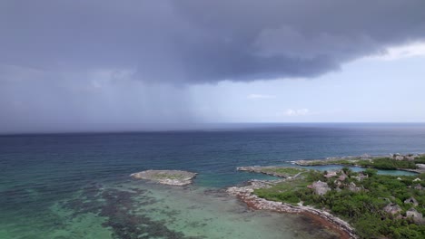 RAIN-IN-THE-CARIBBEAN-SEA-NEXT-TO-AN-ABANDONED-HOTEL-DRONE-SHOOT-TRACKING-SIDEWAYS