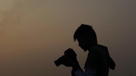 Mann-Mit-Kamera-Fotografiert-Am-Abendlichen-Bewölkten-Himmel,-Silhouette,-Statisch,-Profil