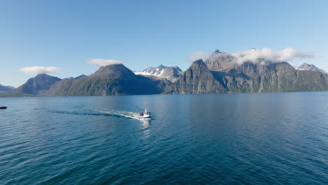 Barco-De-Pesca-Navegando-En-El-Fiordo-De-Lyngen-Con-Los-Alpes-Escandinavos-En-El-Fondo,-Noruega