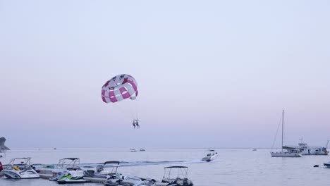 Couple-parasailing-at-the-sea,-boat-tows-parachute