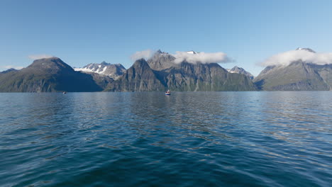 Filmische-Ansicht-Der-Norwegischen-Landschaft-Am-Sommertag-Mit-Fischerboot-Im-Lyngenfjord-Und-Felsigen-Bergen-Der-Skandinavischen-Alpen-Im-Hintergrund,-Norwegen