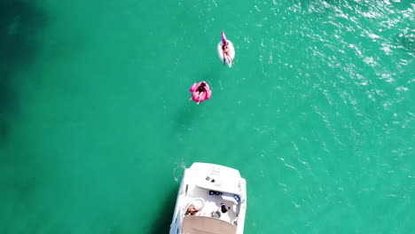 Aerial-top-down-view-of-people-on-a-white-yacht-and-inflatables-enjoying-their-vacation-in-the-caribbean-in-the-Mayan-Riviera,-México