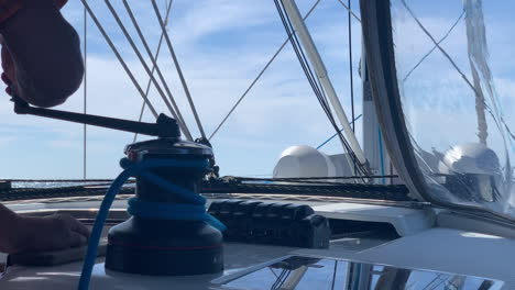 Man-lowering-down-the-sail-of-a-sailing-boat-with-a-blue-bright-sky