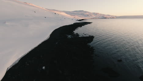 Black-sand-beach-and-snowy-shore-from-above-in-winter