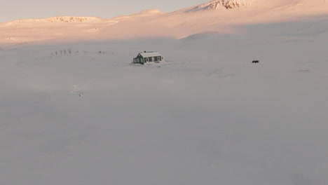 Orbit-around-frozen-cabin-in-snowy-mountains-during-sunset