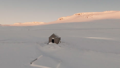 Fpv-dolly-forward-above-abandoned-cabin-towards-mountains-at-sunrise