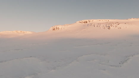 Snowy-scenery-with-winter-mountain-range-at-sunset,-fpv-dolly-forward