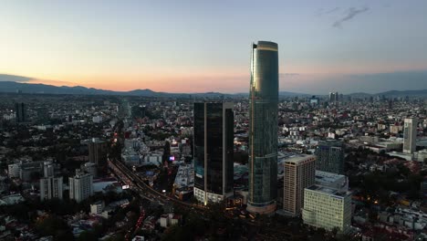 Aerial-view-overlooking-the-Avenida-Río-Churubusco-and-the-Mitikah-tower,-dusk-in-Benito-Juárez,-Mexico---circling,-drone-shot