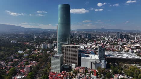 Aerial-view-around-the-Mitikah-building,-in-sunny-Coyoacan,-Mexico-city---orbit,-drone-shot