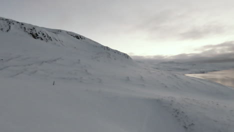 Fpv-dolly-forward-above-snowy-mountains-in-winter-time,-Iceland