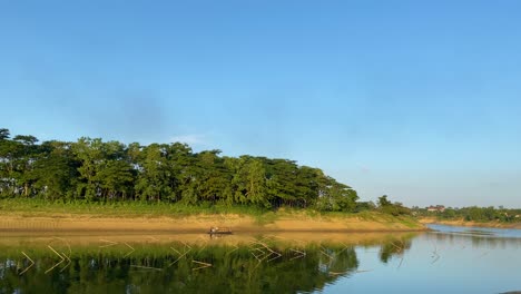Peaceful-scene-of-fisherman-motoring-boat-on-Surma-River,-establisher-wide-view