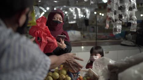 Un-Ama-De-Casa-Con-Una-Máscara-Mientras-Compra-Varias-Verduras-En-El-Mercado-Central-Muestra-Pagos-Atrasados-Con-Transacciones-En-Línea,-Y-El-Vendedor-Le-Da-Las-Verduras-Que-Compró,-Covid-19-Situación