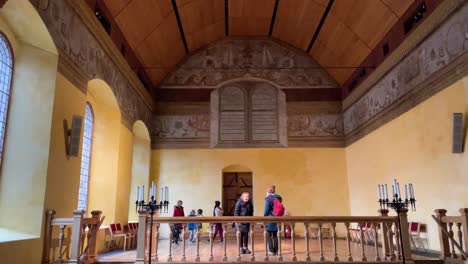 Hand-held-shot-of-a-painted-fake-window-within-Stirling-Castle-with-tourists-exploring