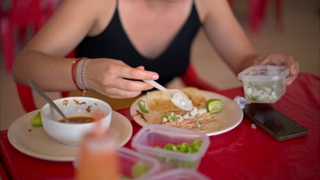 Zeitlupe-Nahaufnahme-Einer-Lateinamerikanischen-Frau,-Die-Ihren-Barbacoa-Taco-Mit-Gehackten-Zwiebeln-Und-Koriander-In-Einem-Restaurant-In-Mexiko-Zubereitet