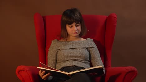 Ein-Mädchen-Sitzt-Auf-Einem-Roten-Stuhl-Und-Liest-Ein-Weihnachtsgeschichtenbuch