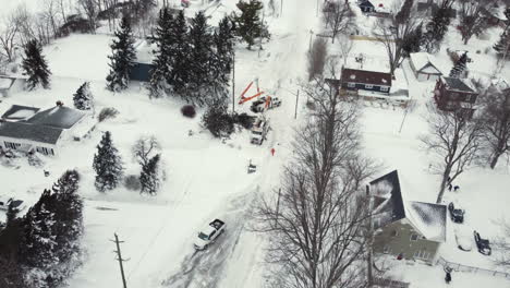 Aerial-drone-footage-of-linemen-restoring-electricity-after-winter-storm,-working-diligently-to-clear-a-fallen-tree-blocking-power-lines