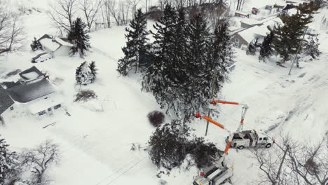 aerial-shot-of-Bucket-trucks-fix-utility-poles-next-to-snow-buried-houses-in-Fort-Erie,-Ontario,-Canada-after-severe-snowstorm