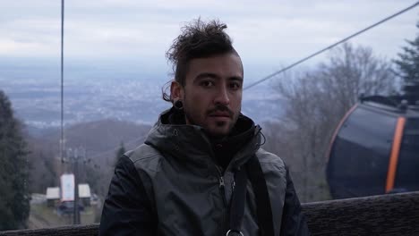 Portrait-of-a-man-who's-scared-of-heights-that-takes-a-cable-lift-up-the-mountain