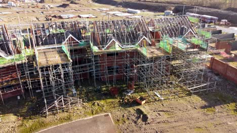 Unfinished-townhouse-framework-and-building-materials-abandoned-on-development-construction-site,-Aerial-view