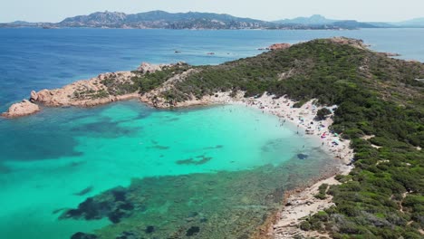 La-Maddalena-Island,-Caprera,-Sardinia---Tourist-People-Swim-and-Relax-at-Cala-Andreani-Beach-in-Blue-Bay---Aerial-4k