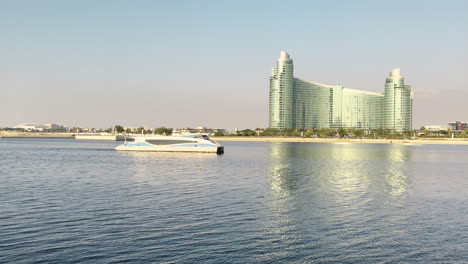 Lujoso-Yate-Navegando-En-El-Arroyo-Dubai-Frente-A-Un-Hotel-Futurista