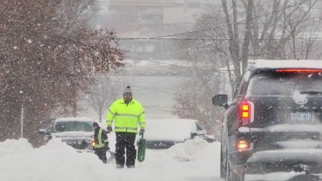 Man-walking-on-snowy-road-during-North-American-winter-storm-Elliot,-establishing-shot
