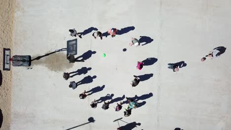 Top-down-drone-shot-of-kids-playing-out-in-the-schoolyard-at-break