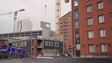 Concrete-wall-element-being-hoisted-to-it's-place-in-an-apartment-house-under-construction