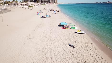 Aerial-shot-of-a-white-sand-beach-in-Mexico-with-tourists-sunbathing-and-enjoying-the-tropical-water