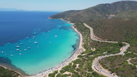 Sardinia-Coastal-Road-near-long-sandy-beach-and-turquoise-blue-mediterranean-sea---Aerial-4k