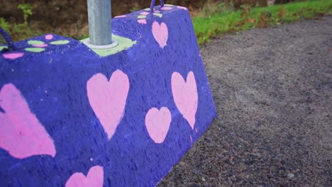 Colourful-concrete-roadblock-with-painted-hearts-on-a-gravel-sidewalk