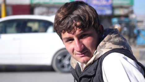 Young-Male-Pakistani-Looking-At-Camera-In-Street-In-Quetta-With-Blurred-Traffic-Going-Past-In-Background