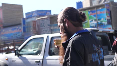 Hombre-Pakistaní-Con-Barba-Larga-Bebiendo-Lentamente-Una-Bebida-En-La-Calle-En-Quetta