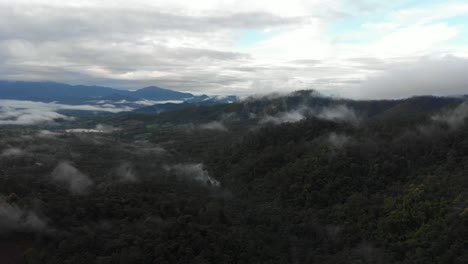 Drone-fly-over-the-remote-countryside-forest-hills-of-Pai,-Thailand-covered-in-rolling-hills-of-trees-and-very-low-thick-inversion-cloud-during-monsoon-season