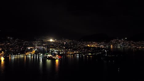 Aerial-night-view-of-Bergen-Norway-with-small-fireworks-explode-throughout-city-during-new-year-celebration