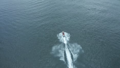 Aerial,-jet-ski-sailing-fast-on-lake-during-the-day
