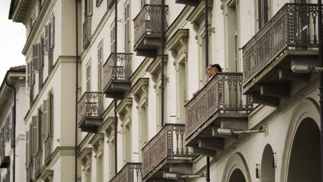 Man-and-woman-filming-from-Italian-balcony-with-cellphone