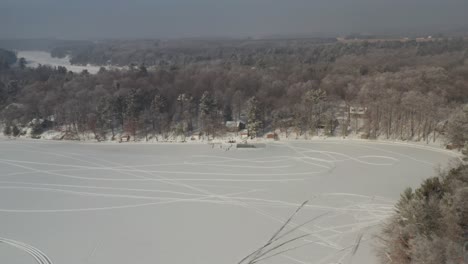 Aerial,-snowmobile-tracks-on-a-snow-covered-frozen-lake-during-winter