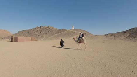 Hurgada,-Egypt-29-December-2022:-the-Camels-in-Sahara-Desert,-Egypt,-traditional-Dressed-Bedouins-Riding-Tourists-on-Camels-Through-Sandy-Desert