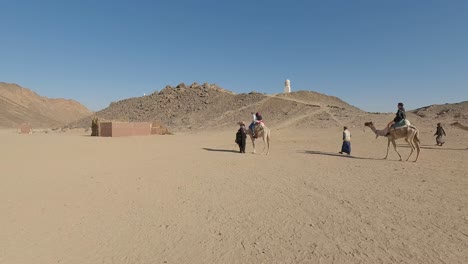 Hurgada,-Egypt-29-December-2022:-the-Camels-in-Sahara-Desert,-Egypt,-traditional-Dressed-Bedouins-Riding-Tourists-on-Camels-Through-Sandy-Desert