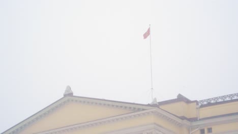 Norwegian-National-Flag-Flying-Above-The-Royal-Palace-In-Oslo-During-Heavy-Snow