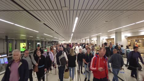 Multitud-De-Pasajeros-Caminando-En-Cola-En-El-Aeropuerto-De-Amsterdam-Schiphol-En-Amsterdam,-Países-Bajos