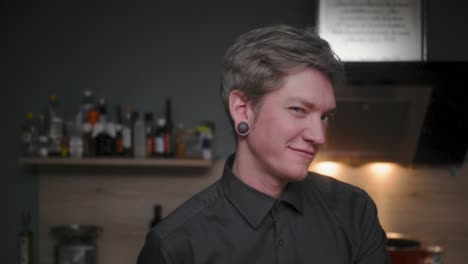 Attractive-professional-male-chef-in-an-elegant-black-shirt-with-an-alternative-look-throwing-a-mushroom-in-the-ai,-winking-into-camera-Modern,-fancy-kitchen,-Slow-Motion-4K