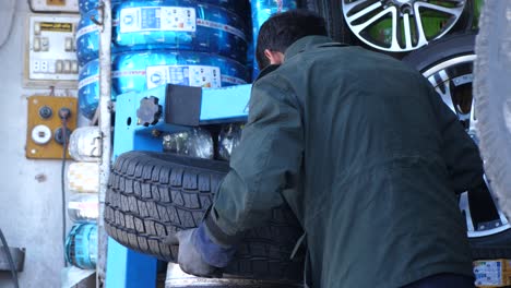 View-Behind-Car-Mechanic-Changing-Car-Tyre-In-Quetta,-Balochistan
