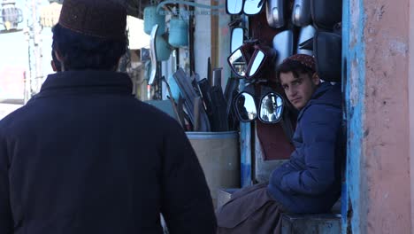 Locals-Walking-Past-Car-Parts-Shop-In-Street-In-Quetta,-Balochistan
