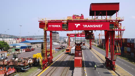 Wide-aerial-drone-shot-of-a-saddle-crane-lifting-a-shipping-container