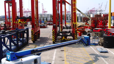 Aerial-drone-rising-shot-of-a-saddle-crane-in-a-shipping-container-yard-with-gantry-cranes-in-the-distance