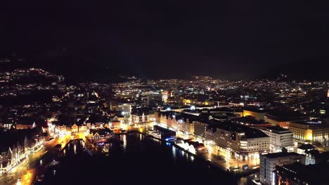 Vaagen-and-Bergen-city-center-at-new-years-eve-midnight---Beautiful-night-aerial-Showing-illuminated-city-and-random-fireworks-in-background---Norway